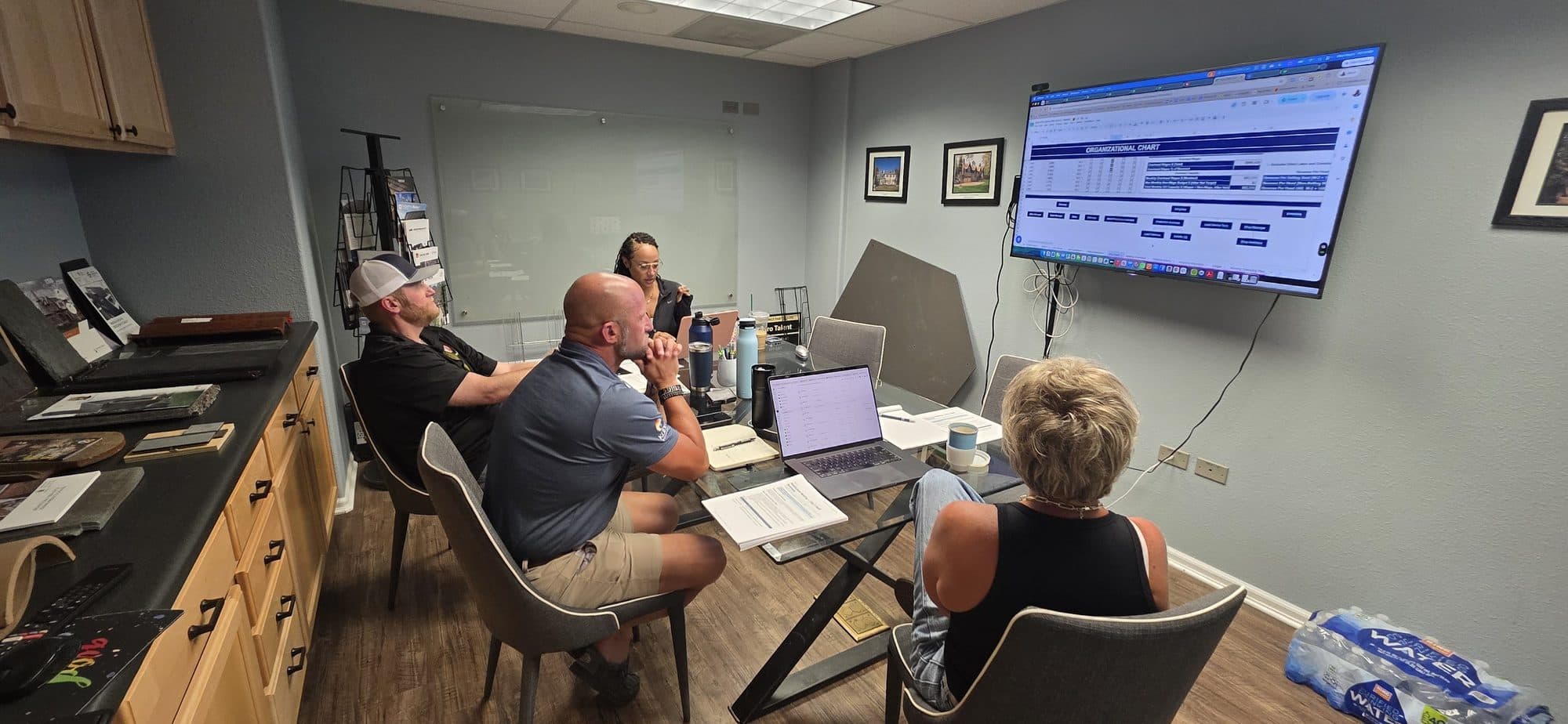 A member team works through a dashboard on the wall screen with a Roofing Academy coach.